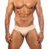 Men's swimwear, briefs style, worn by a man, front view, sand color background.