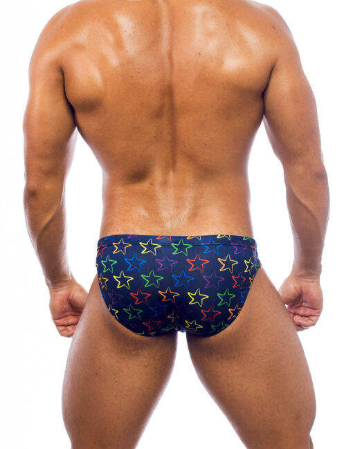 Men's swimwear, slip style, worn by a man, rear view, design of the outline of colorful starfish, symbol of the brand, on an ultramarine blue background.