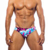 Men's swimwear, slip style, worn by a man, front view, camouflage pattern with blue, pink, white and brown colors.